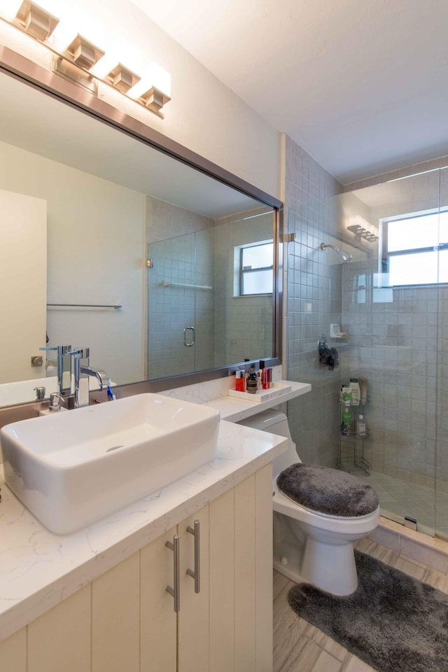 bathroom with hardwood / wood-style floors, vanity, toilet, and a shower with door