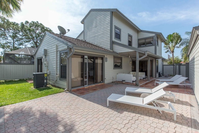 rear view of property with a yard, a patio, central AC, and a lanai