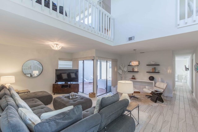 living room with a towering ceiling and light hardwood / wood-style flooring