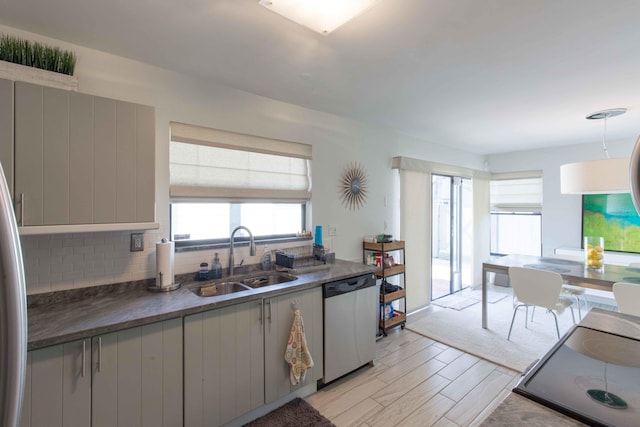 kitchen with decorative backsplash, stainless steel dishwasher, sink, light hardwood / wood-style flooring, and range