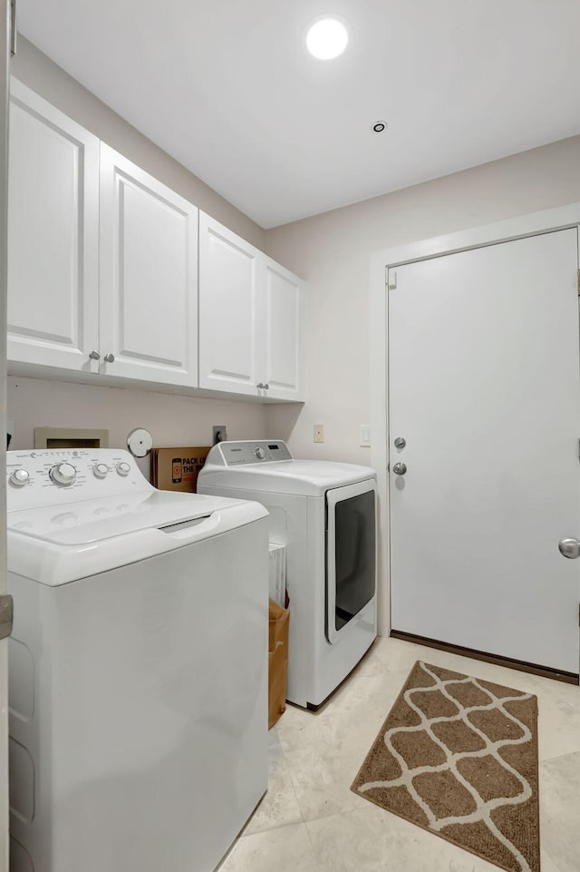 clothes washing area with cabinets and washing machine and clothes dryer