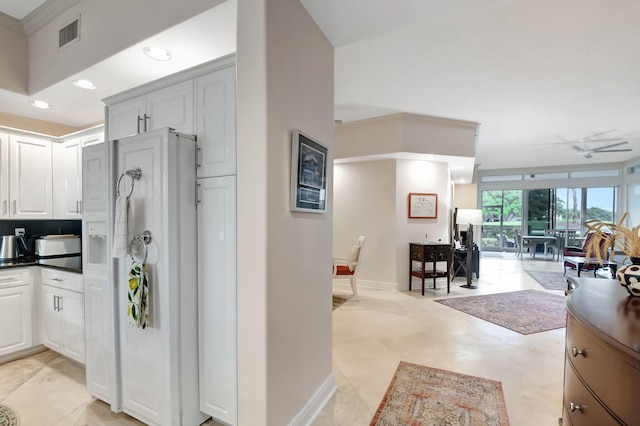 kitchen with white cabinetry, white fridge with ice dispenser, and ceiling fan