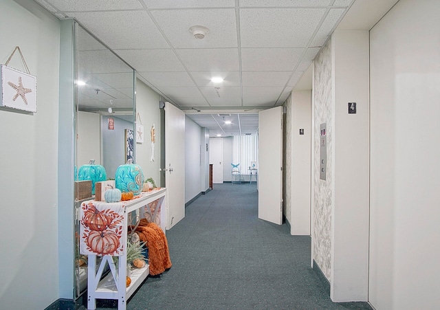 corridor with a paneled ceiling, elevator, and carpet flooring