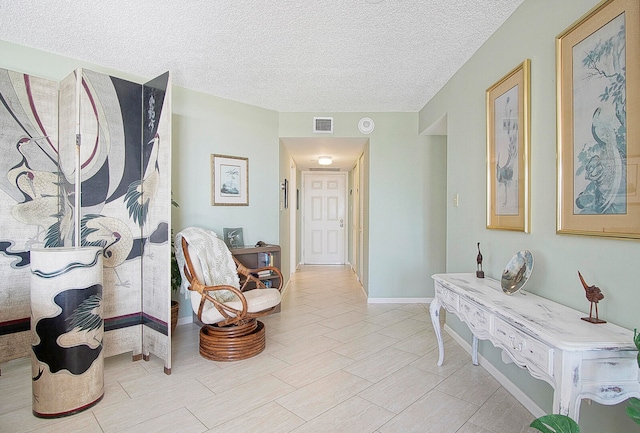 corridor featuring a textured ceiling, visible vents, and baseboards