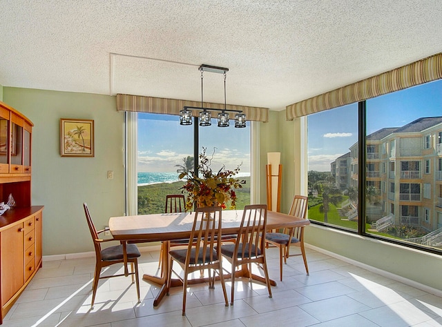 dining space featuring a notable chandelier, a textured ceiling, baseboards, and a wealth of natural light