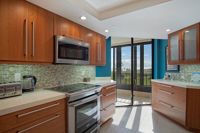 kitchen with decorative backsplash, appliances with stainless steel finishes, and light tile patterned floors