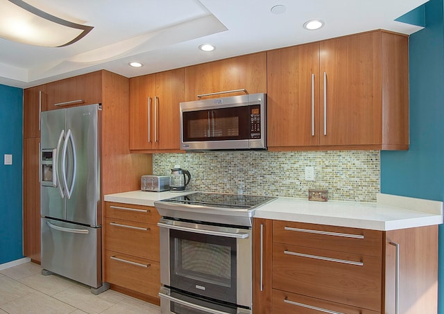 kitchen with brown cabinetry, tasteful backsplash, stainless steel appliances, and light tile patterned flooring