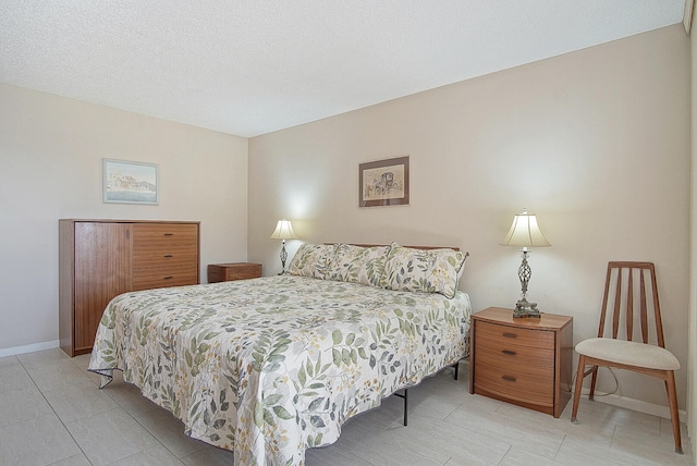 bedroom with a textured ceiling and baseboards