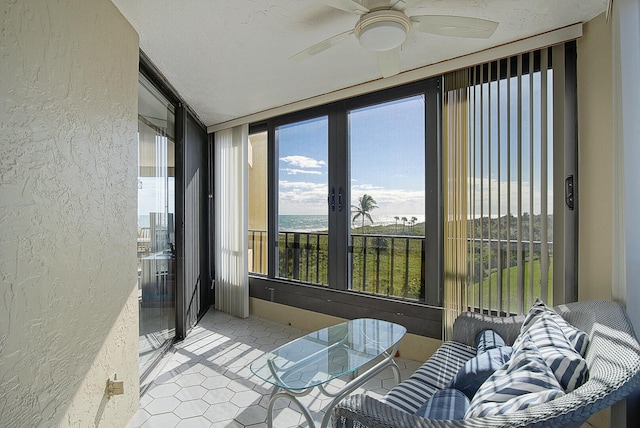 sunroom / solarium featuring ceiling fan and a water view