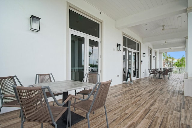 wooden terrace with ceiling fan, outdoor dining area, and french doors