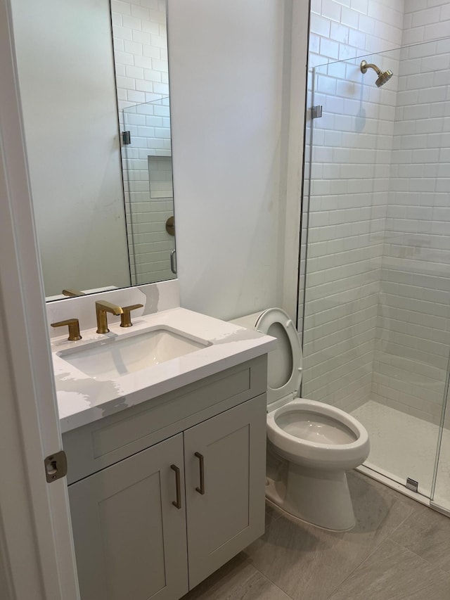 bathroom featuring tile patterned floors, toilet, a stall shower, and vanity