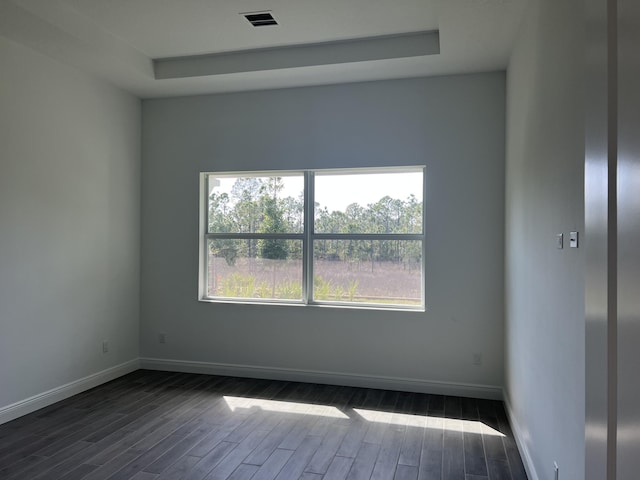 unfurnished room featuring visible vents, baseboards, a raised ceiling, and dark wood-style flooring