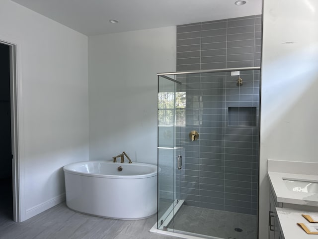 full bath with a shower stall, vanity, baseboards, and a freestanding tub