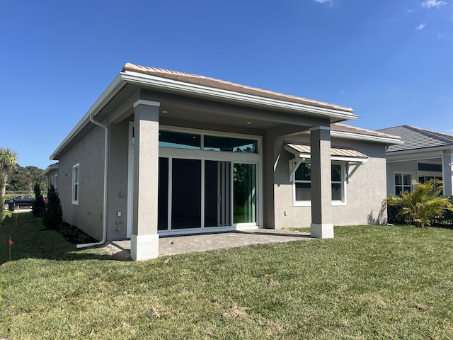 back of house with a patio, a lawn, and stucco siding