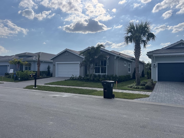 ranch-style house featuring an attached garage, a tile roof, decorative driveway, and a front lawn