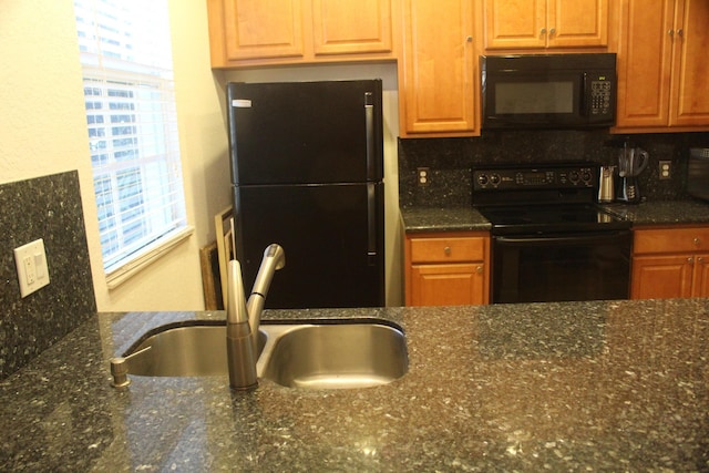 kitchen with tasteful backsplash, dark stone countertops, sink, and black appliances