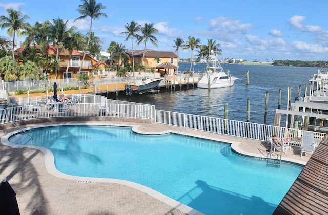 view of swimming pool with a boat dock, a patio, and a water view