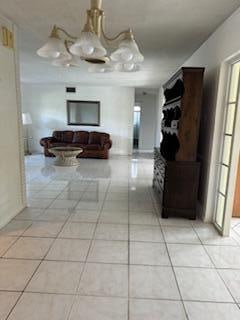 hall featuring plenty of natural light, light tile patterned floors, and an inviting chandelier