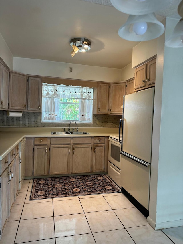 kitchen featuring decorative backsplash, stainless steel fridge, white range, sink, and light tile patterned floors