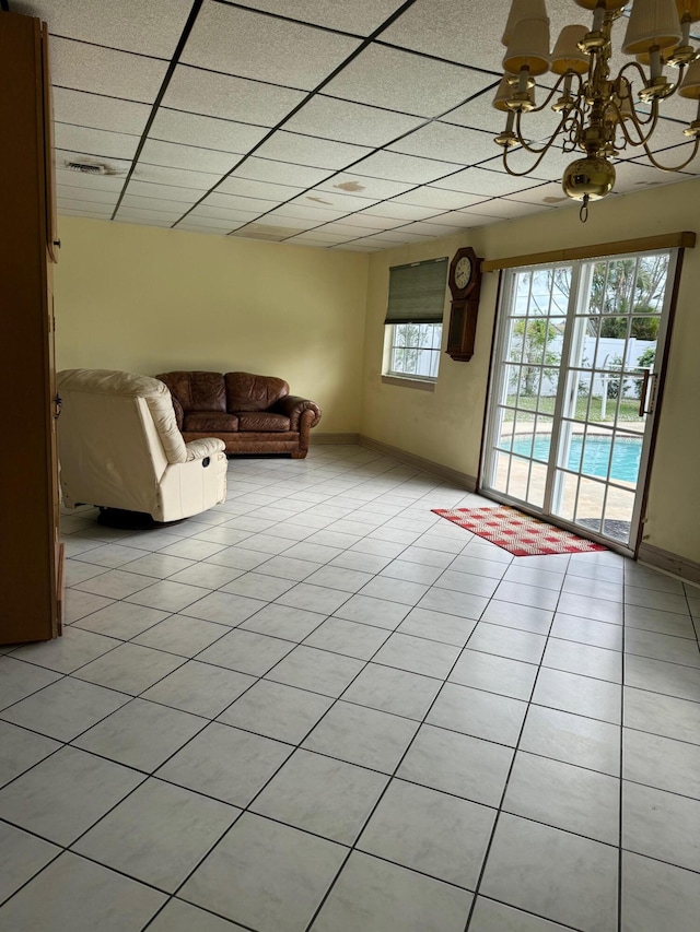 unfurnished living room featuring a paneled ceiling, light tile patterned flooring, and a chandelier