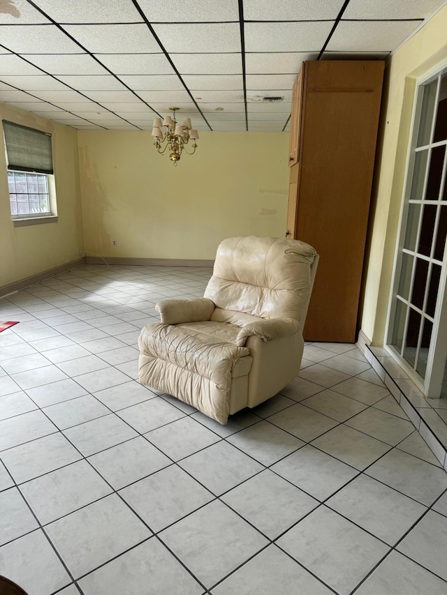 unfurnished room with a paneled ceiling, light tile patterned floors, and an inviting chandelier