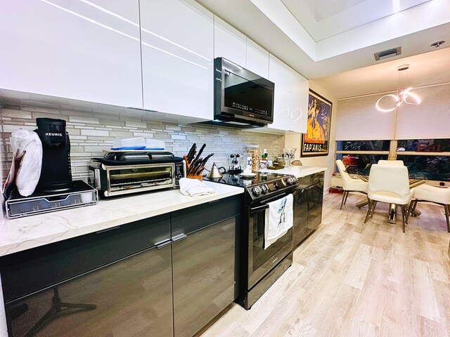 kitchen featuring tasteful backsplash, white cabinetry, sink, a tray ceiling, and light hardwood / wood-style flooring