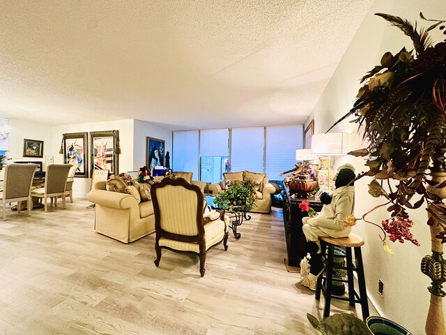 living room featuring an inviting chandelier, expansive windows, light hardwood / wood-style floors, and a textured ceiling