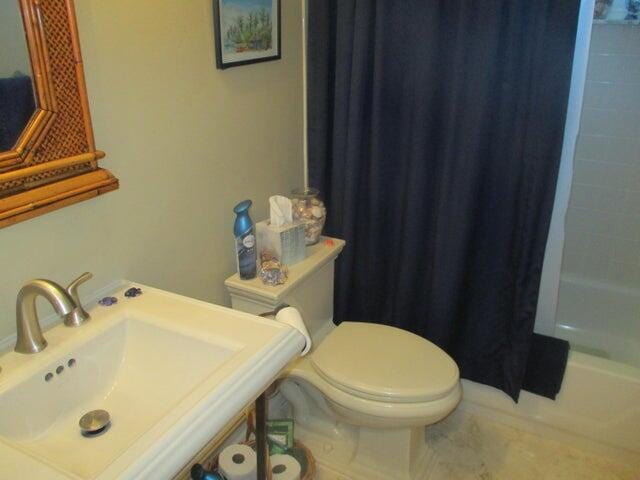 full bathroom featuring toilet, shower / bathtub combination with curtain, and sink