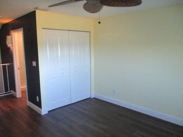 unfurnished bedroom with a closet, ceiling fan, and dark hardwood / wood-style flooring