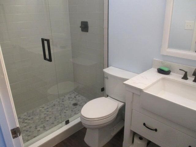 bathroom with vanity, toilet, and a shower with door