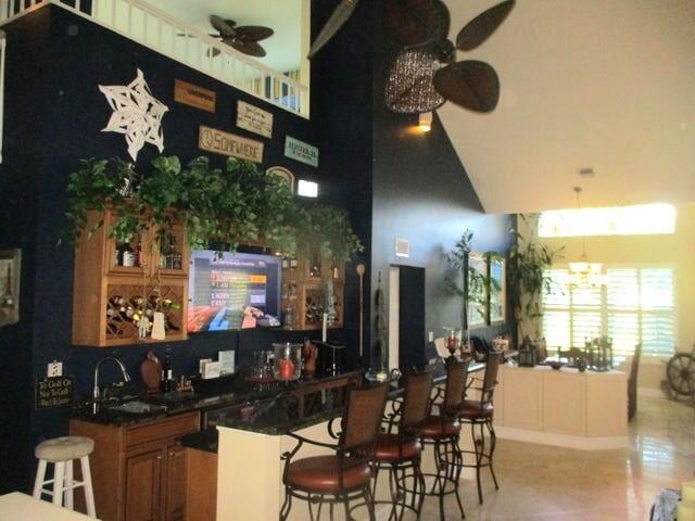 bar featuring light tile patterned flooring, ceiling fan, and sink