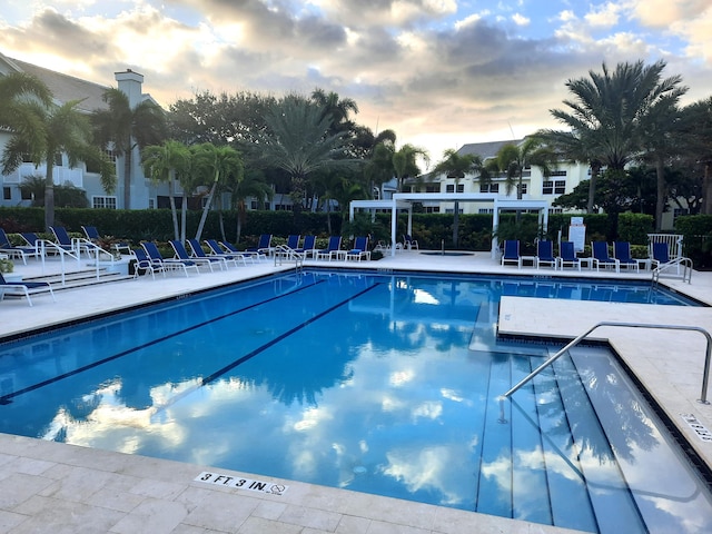 pool at dusk featuring a patio area