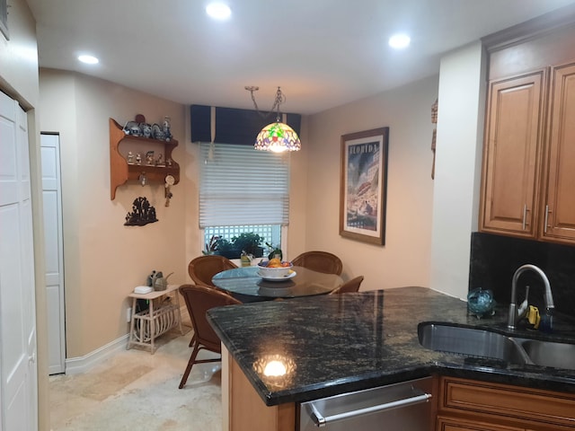 kitchen featuring pendant lighting, dishwasher, sink, and dark stone counters