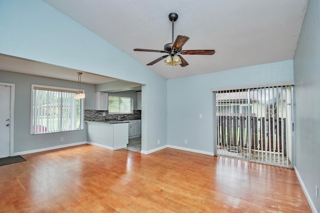 unfurnished living room with ceiling fan, light hardwood / wood-style floors, and vaulted ceiling