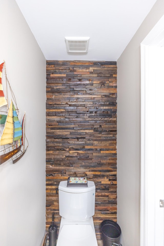 bathroom featuring wooden walls and toilet