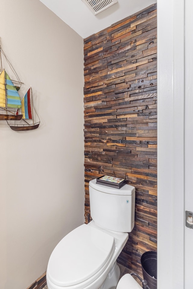 bathroom featuring toilet and wood walls