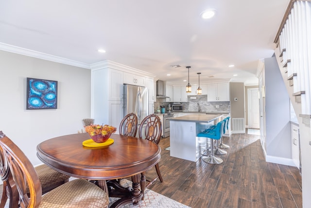 dining area with dark hardwood / wood-style floors, ornamental molding, and sink