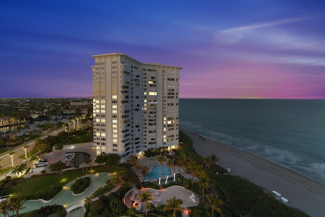 outdoor building at dusk featuring a water view and a view of the beach