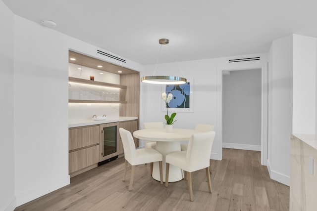 dining space with light hardwood / wood-style flooring and beverage cooler