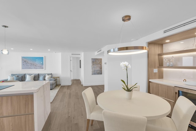 dining space with wine cooler and light hardwood / wood-style flooring