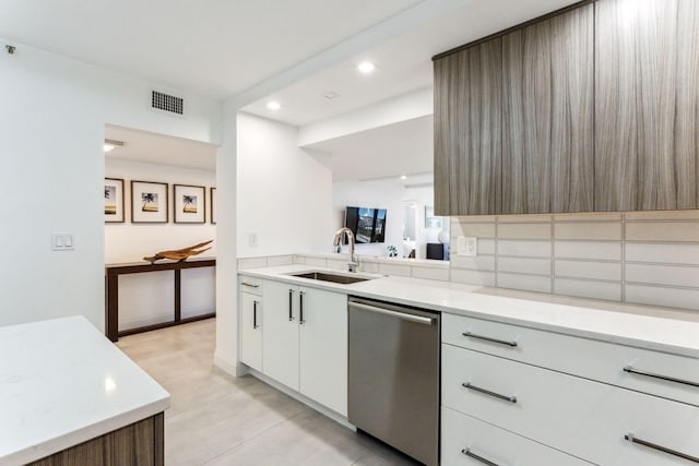 kitchen with white cabinetry, sink, stainless steel dishwasher, and decorative backsplash