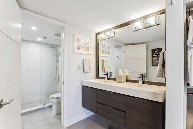 bathroom with tiled shower, vanity, and toilet