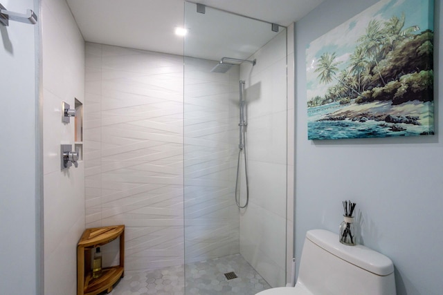 bathroom featuring a tile shower and toilet