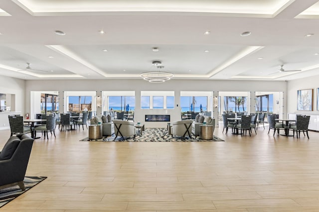 workout area featuring ceiling fan, a raised ceiling, light hardwood / wood-style floors, and a wealth of natural light