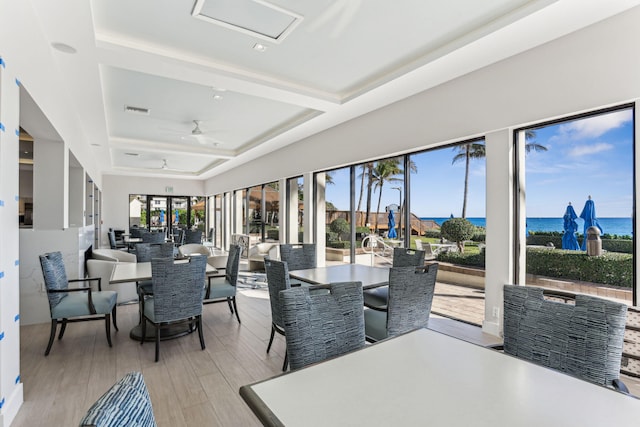 sunroom with a water view, ceiling fan, a healthy amount of sunlight, and a raised ceiling