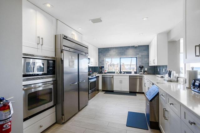 kitchen featuring white cabinetry, decorative backsplash, and appliances with stainless steel finishes