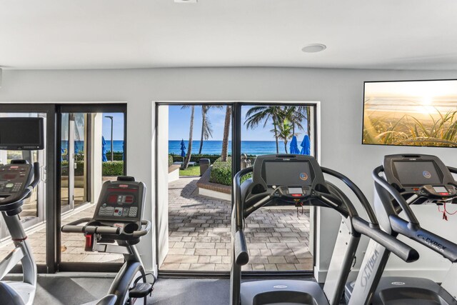 sunroom with a raised ceiling, ceiling fan, and a water view