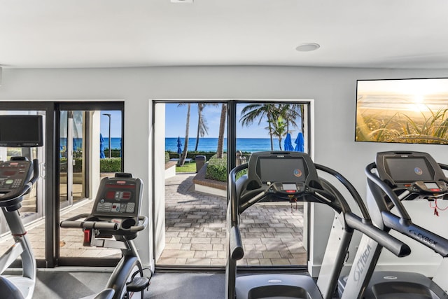 exercise room featuring a wealth of natural light and a water view