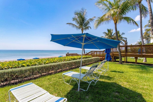 view of yard featuring a deck with water view and a view of the beach