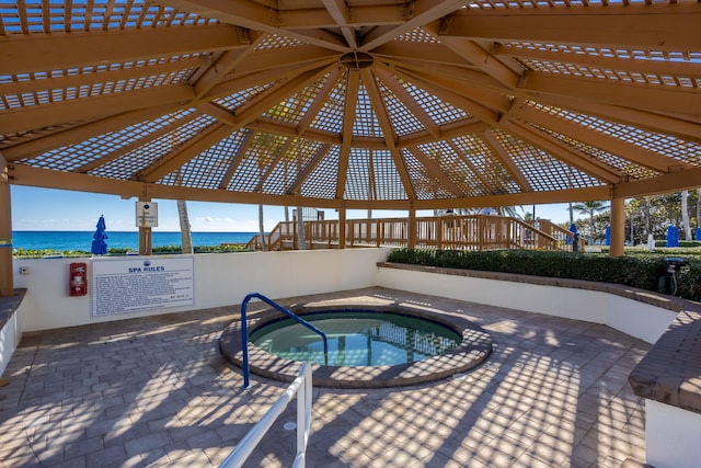 view of pool featuring a water view, a patio, a hot tub, and a gazebo